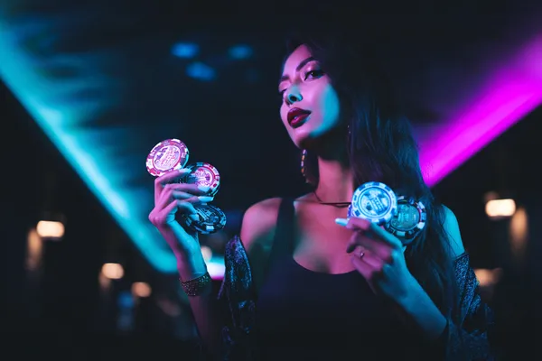 A young woman relaxing with her phone while dynamic casino elements float around her, illustrating the smooth mobile experience offered by the FFBETT app.